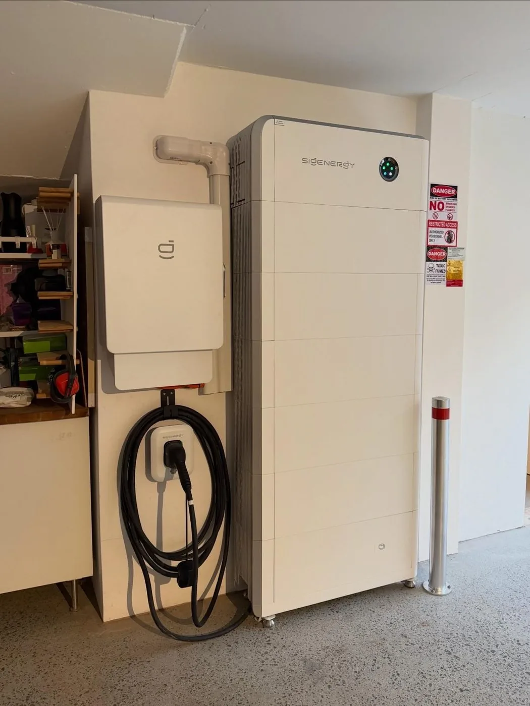Sigenergy battery system and wall-mounted EV charger with coiled cable inside a garage