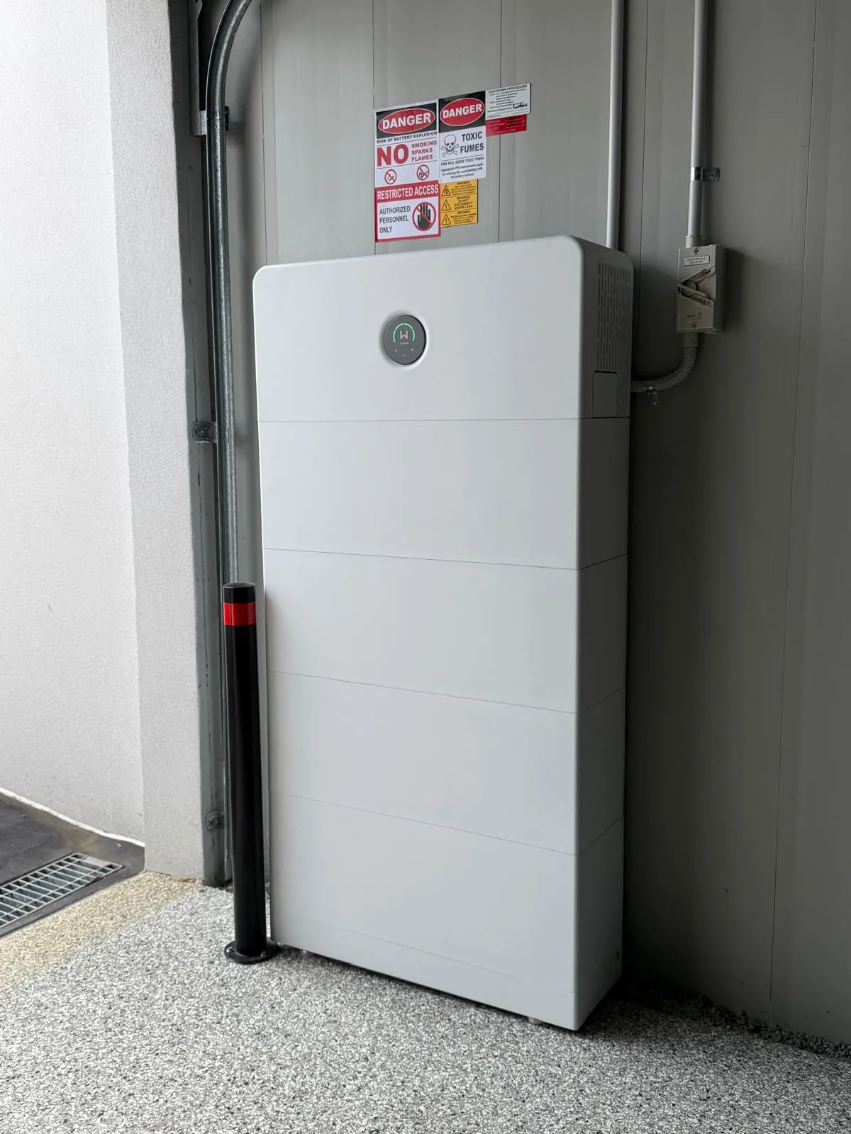 White GoodWe battery stack installed in a garage with a protective bollard