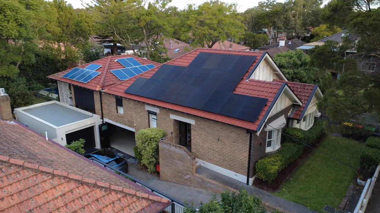 Wide drone view of a red-tiled federation home with solar, surrounded by tall trees