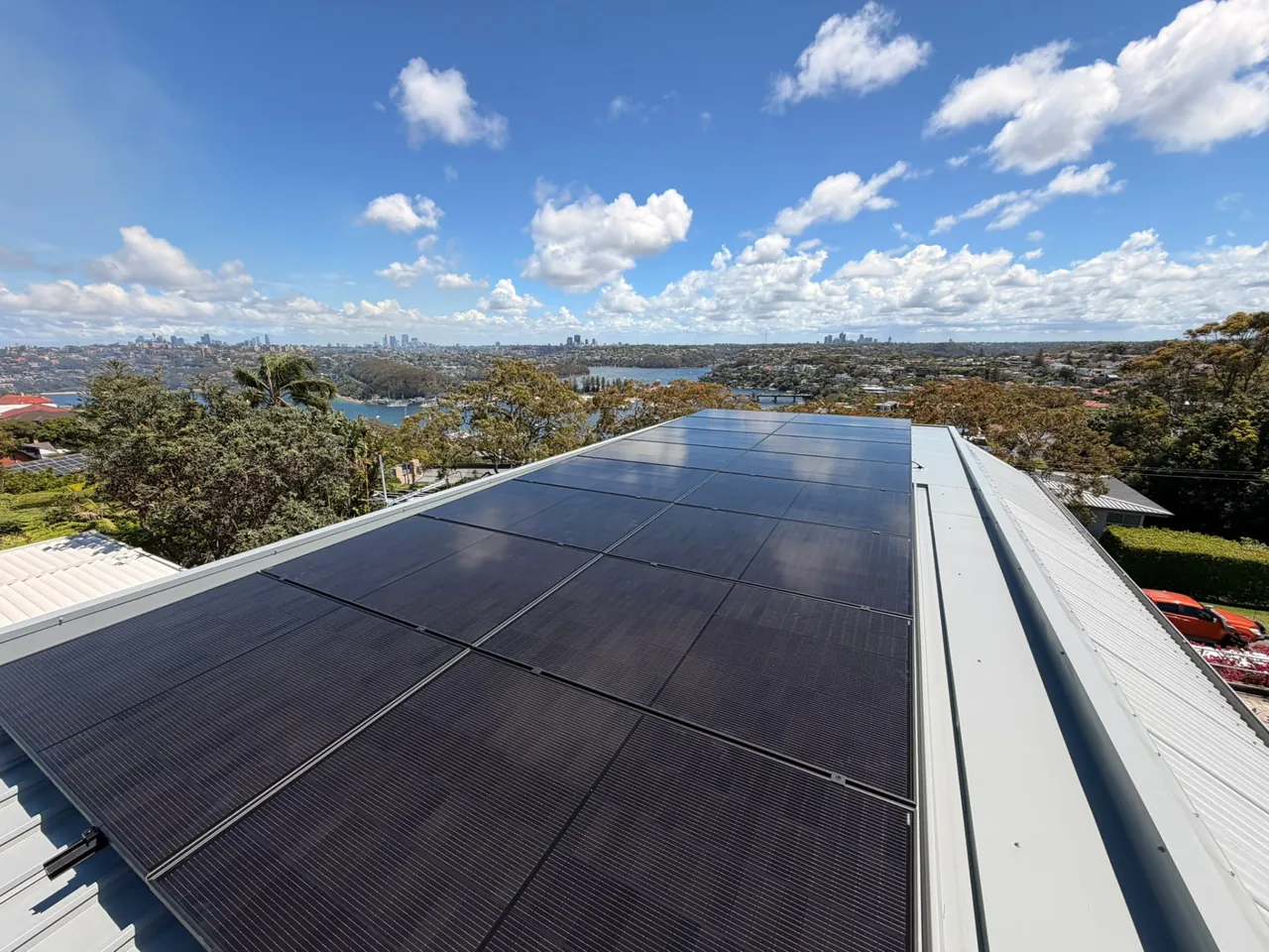 All-black solar panels on a metal roof overlooking Sydney Harbour and the city skyline