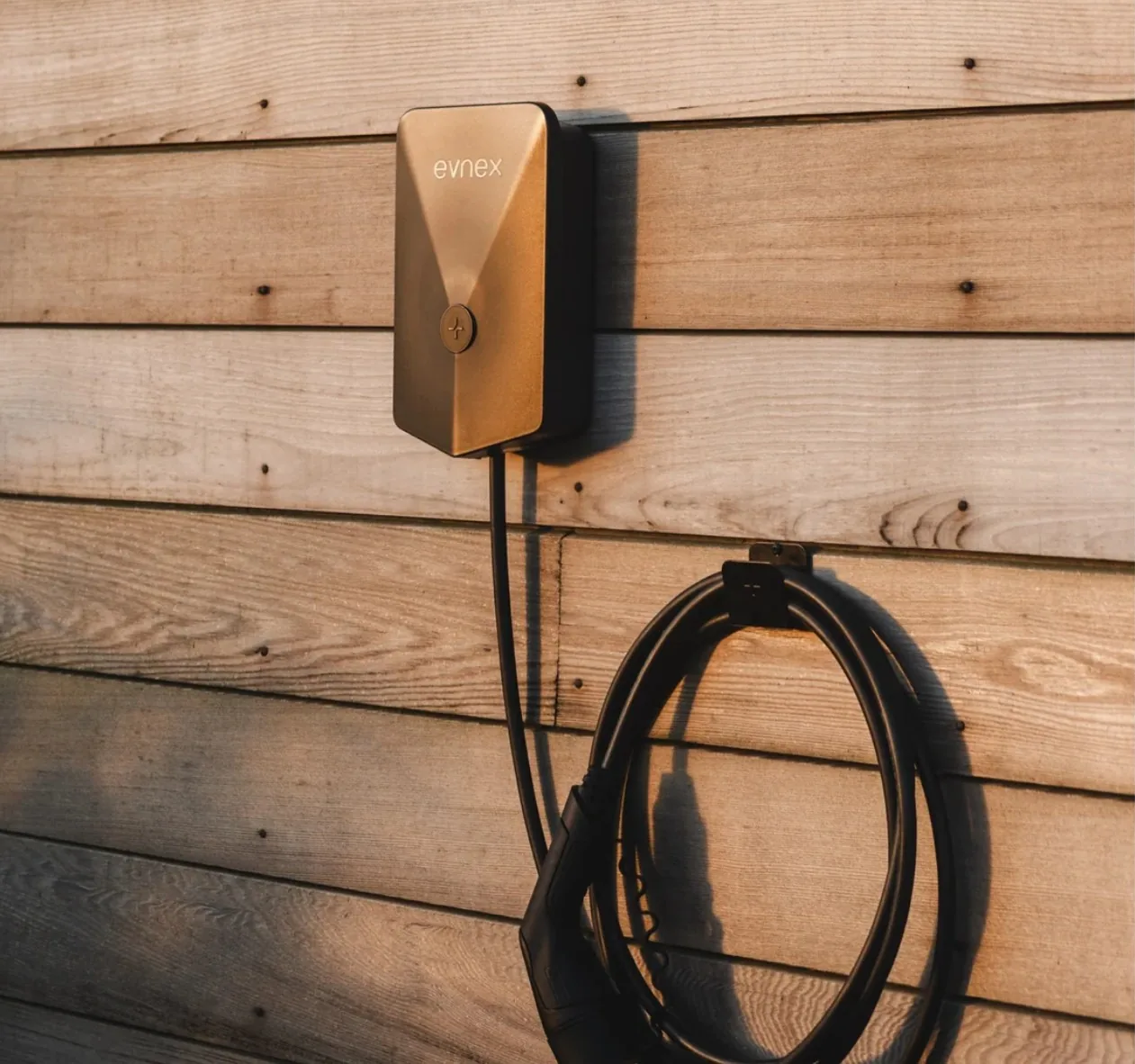 Evnex EV charger mounted on a timber wall with its charging cable coiled on a hook