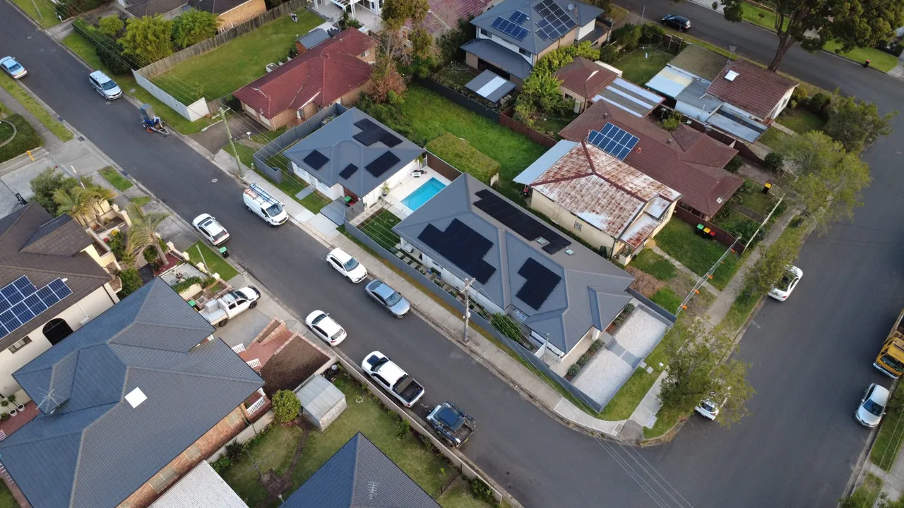 Drone view along a residential street showing several neighbouring roofs with solar