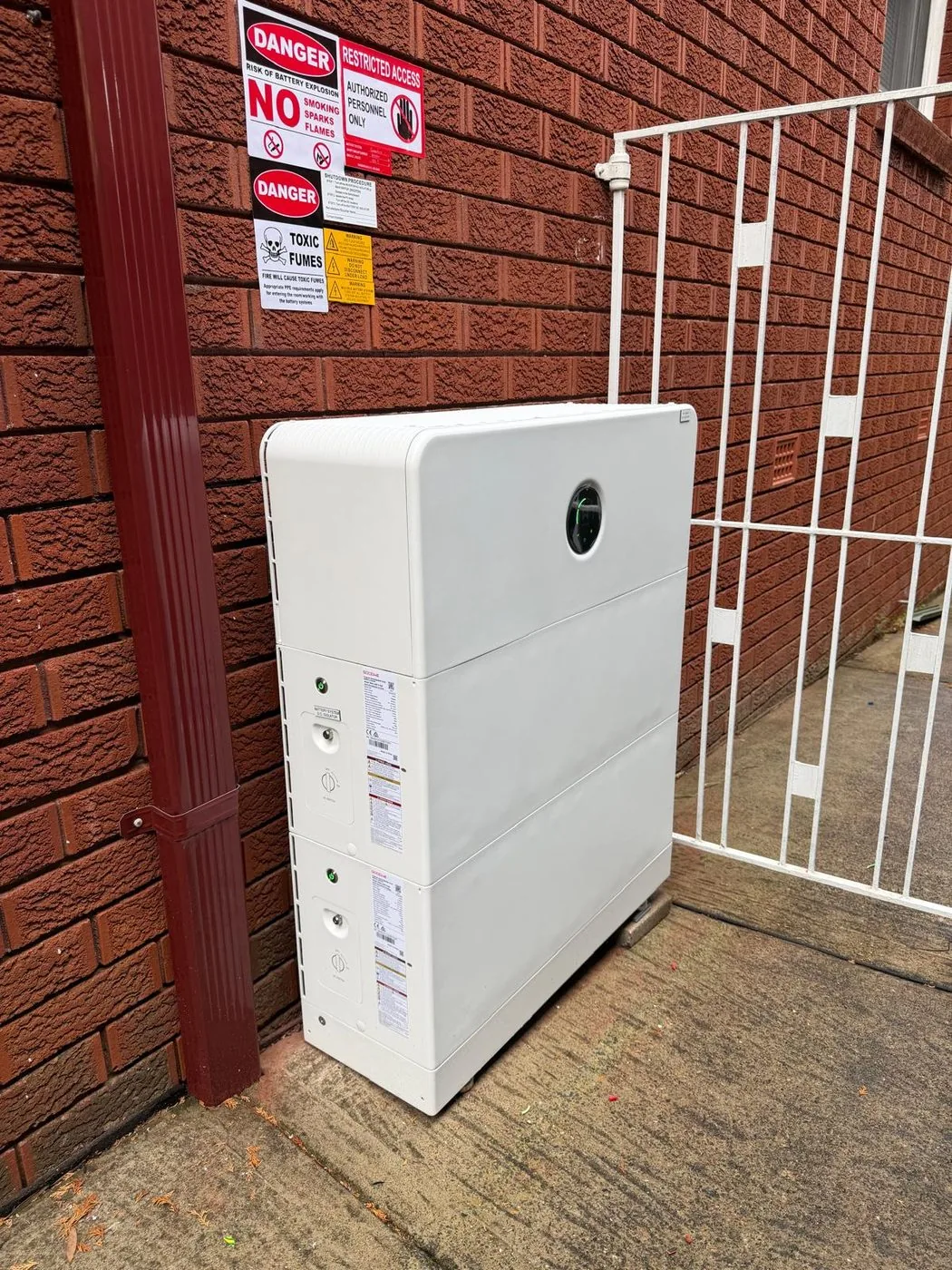 GoodWe ESA battery installed outdoors next to a red brick wall and side gate