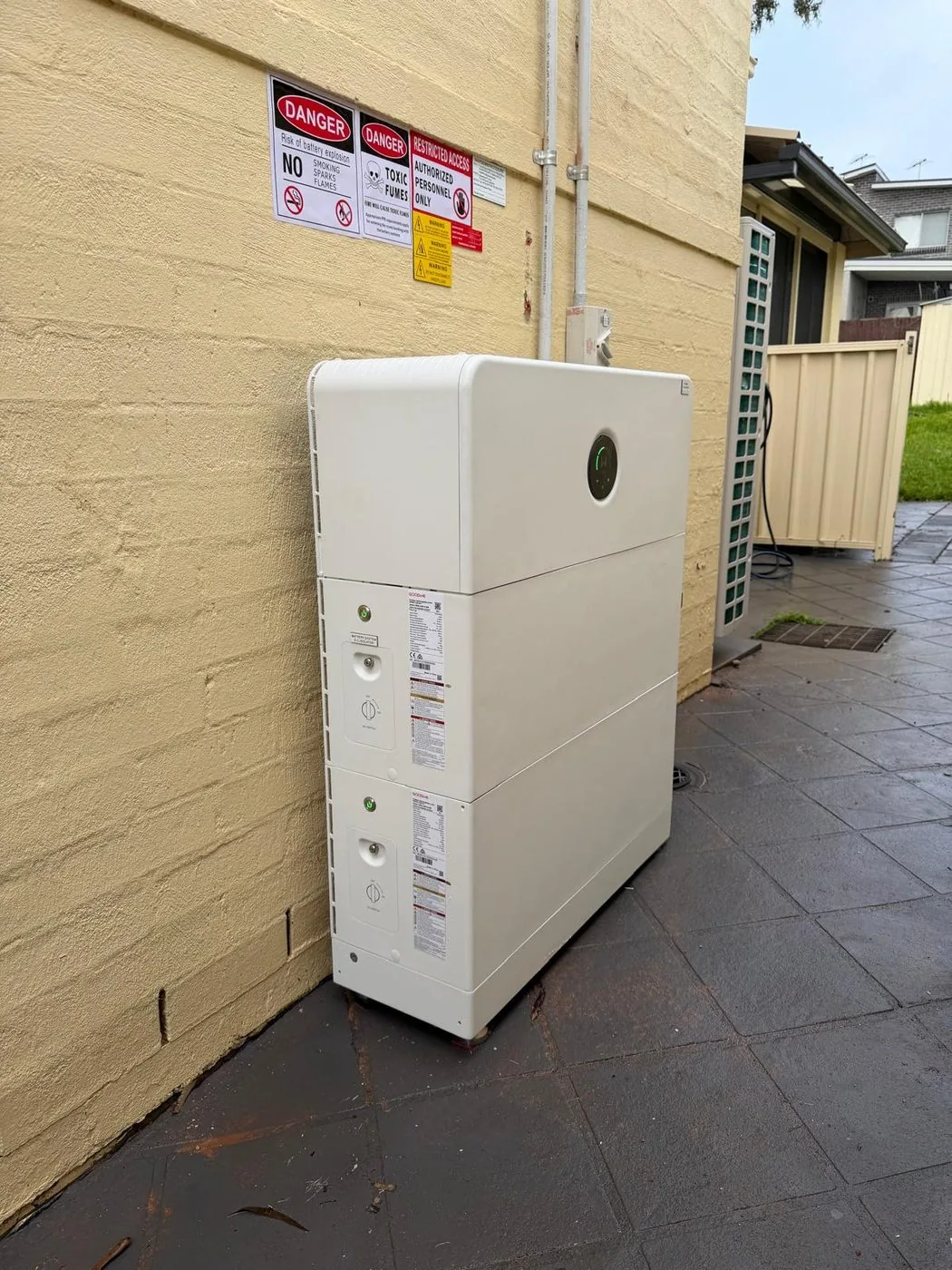 Three-module GoodWe ESA battery standing beside a cream painted brick wall