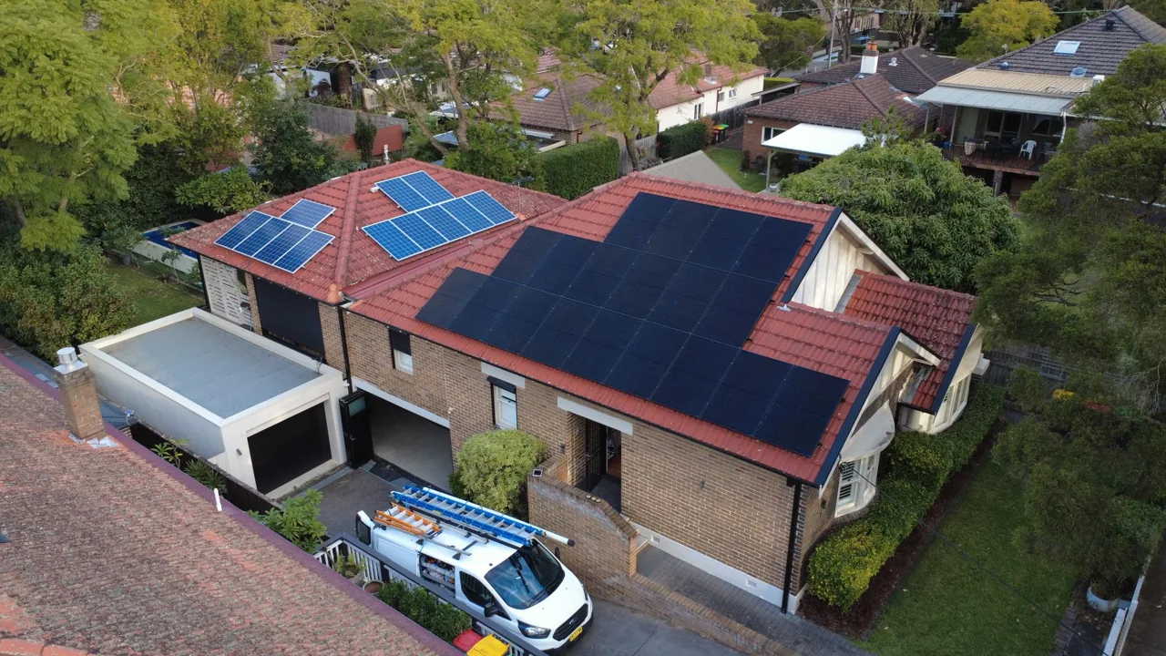Federation-style home with a red terracotta tile roof fitted with solar panels, work vehicle parked below